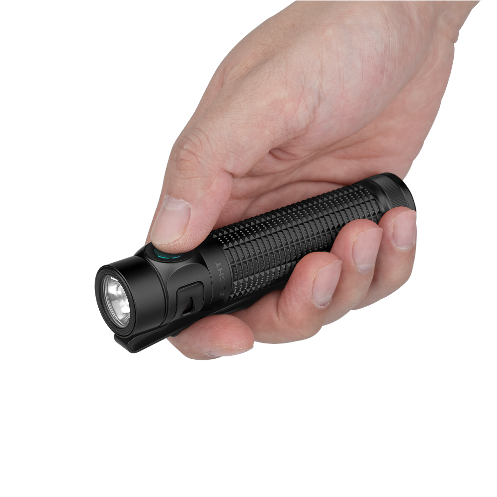 Hand holding a black textured flashlight with a green button and a clear lens.