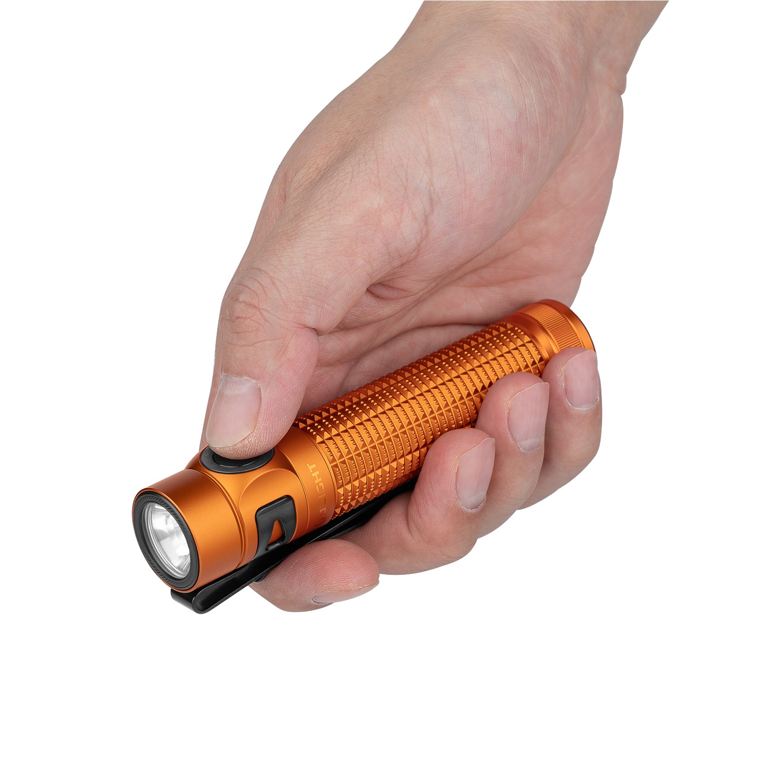 Hand holding an orange flashlight with a textured grip, black clip, and side button against a white background.