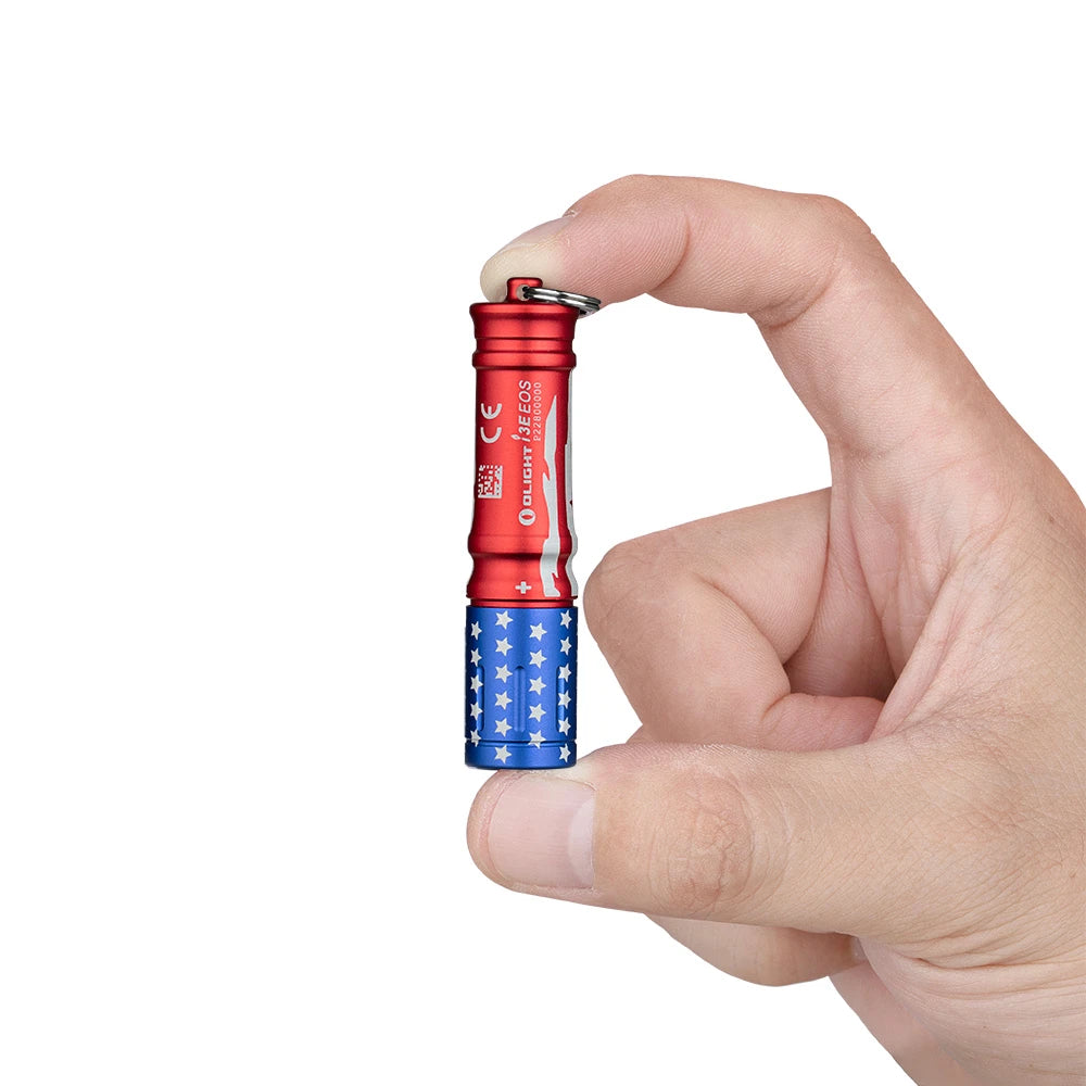 Olight I3E EOS flashlight in red, white, and blue stars and stripes, held by a hand, for everyday carry.