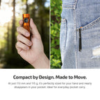 Hand holding compact orange flashlight, flashlight clipped to jean pocket for EDC