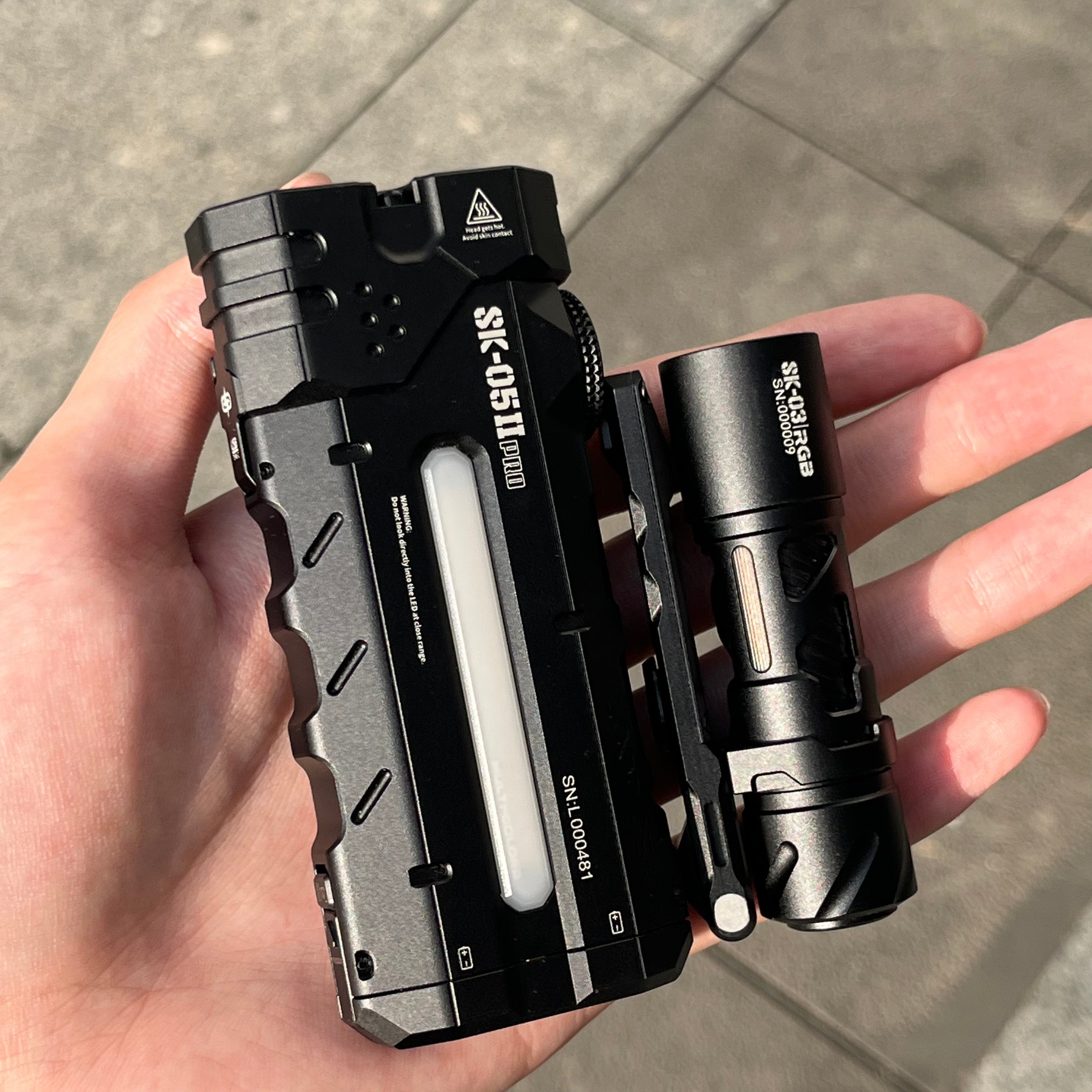 SK05 Pro 2 in Black held in the hand beside a tube torch, showing the flat profile